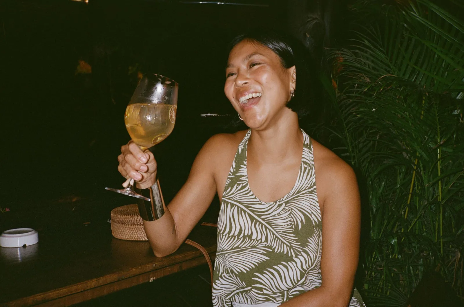 Guest laughing with a glass of wine among the palms at The Lakehouse, Koh Phangan